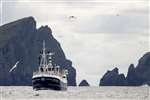 MV Louisa fishing boat with the cliffs of Hirta and Soay, St Kilda